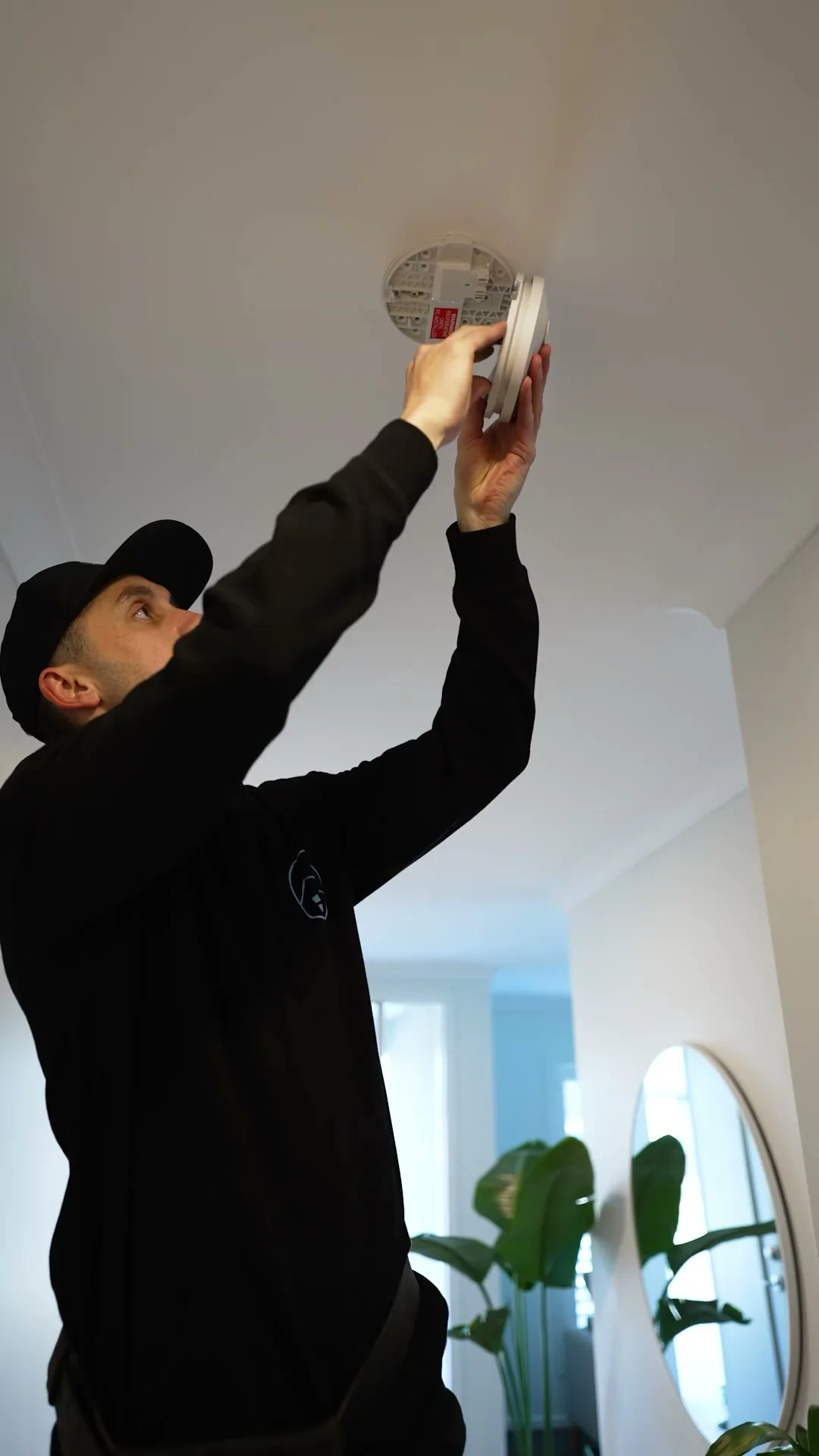 Joel testing a ceiling-mounted smoke alarm during a home visit